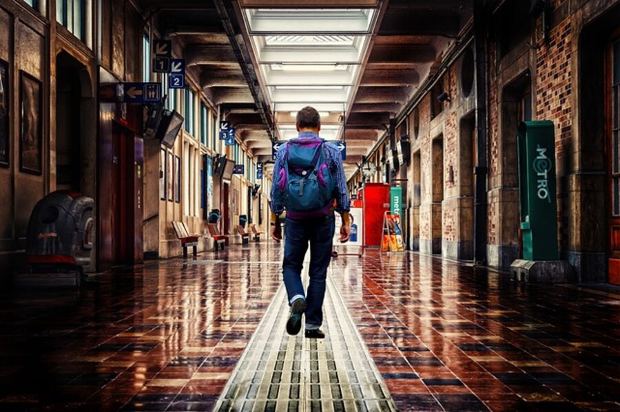 Traveller with backpack walking through a station corridor